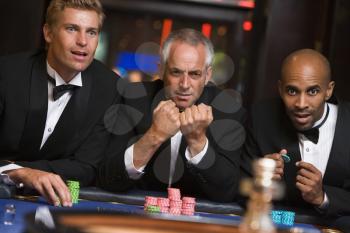 Royalty Free Photo of Three Hopeful Men at a Roulette Table