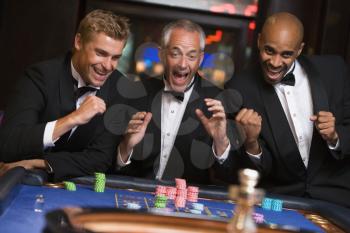 Royalty Free Photo of Three Winning Men at a Roulette Table