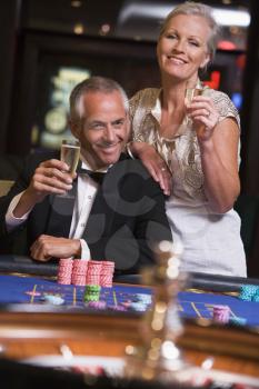 Royalty Free Photo of a Couple With Raising a Glass at a Roulette Table