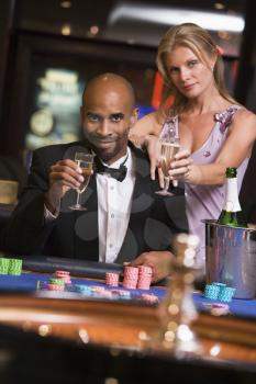 Royalty Free Photo of a Couple With Champagne at the Roulette Table