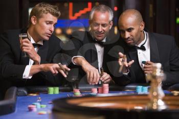 Royalty Free Photo of Three Men Around a Roulette Table