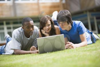 Royalty Free Photo of Students Lying on a Lawn With a Laptop