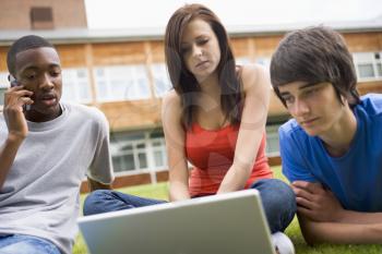 Royalty Free Photo of Three Students With a Laptop and Cellphone