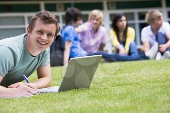Royalty Free Photo of a Student Taking Notes From a Laptop With Other People in the Background