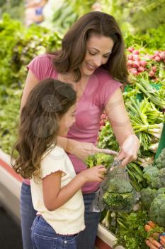 Royalty Free Photo of a Mother and Daughters Shopping for Broccoli