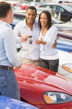 Royalty Free Photo of a Young Couple Getting the Keys for a Car
