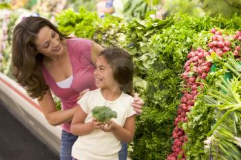 Royalty Free Photo of a Mother and Daughters Shopping for Broccoli