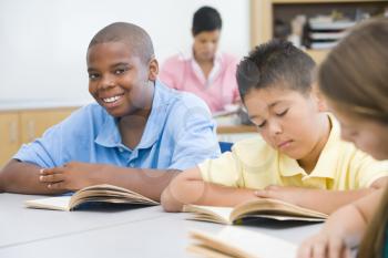 Royalty Free Photo of Students Reading With the Teacher in the Background