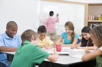 Royalty Free Photo of Students Writing While the Teacher's at the Board