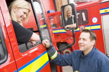 Royalty Free Photo of a Female Firefighter Talking to a Colleague From the Truck