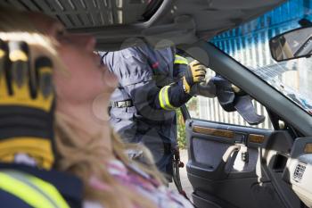 Royalty Free Photo of a Firefighter Cutting a Windshield With a Victim in the Car