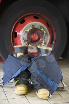 Royalty Free Photo of a Firefighting Suit and Boots by a Truck Wheel