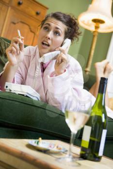 Royalty Free Photo of a Woman Sipping Wine and Smoking While Talking on the Telephone