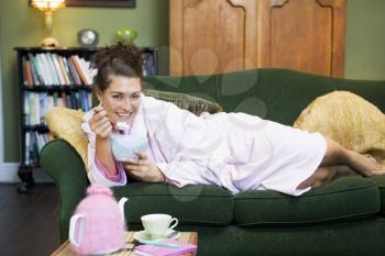 Royalty Free Photo of a Woman Lying on a Sofa Eating a Sweet Treat