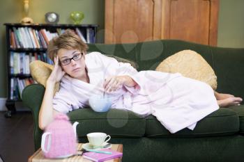 Royalty Free Photo of a Young Woman on the Sofa Eating a Sweet Treat
