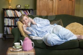 Royalty Free Photo of a Young Woman Lying on the Couch Talking on the Phone