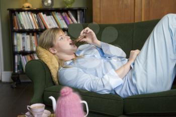 Royalty Free Photo of a Young Woman Lying on the Sofa Eating Chocolate