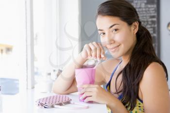 Royalty Free Photo of a Young Woman Sitting and Sipping a Drink