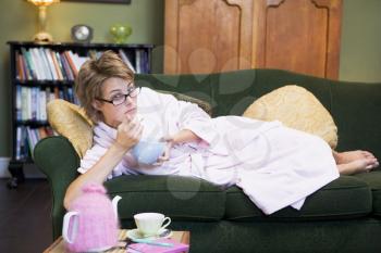 Royalty Free Photo of a Woman Lying on a Sofa Eating a Bowl of Food