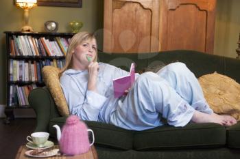 Royalty Free Photo of a Young Woman on a Sofa Writing in Her Diary