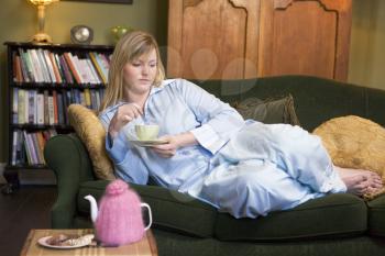 Royalty Free Photo of a Young Woman Drinking Tea While Lying on the Sofa