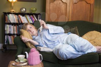 Royalty Free Photo of a Woman Lying on the Sofa Holding a Telephone