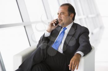 Royalty Free Photo of a Man Sitting in a Chair With a Cellphone