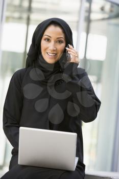 Royalty Free Photo of an Eastern Woman With a Laptop and Cellphone