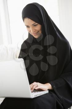 Woman in living room on laptop smiling (high key/selective focus)