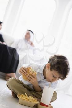 Royalty Free Photo of a Boy Eating Fast Food With His Parents Behind Him