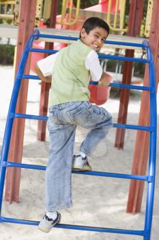 Royalty Free Photo of a Young Boy Climbing Playground Equipment