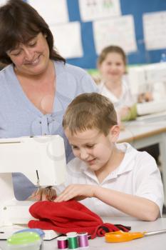 Royalty Free Photo of a Boy Sewing With His Teacher Behind Him
