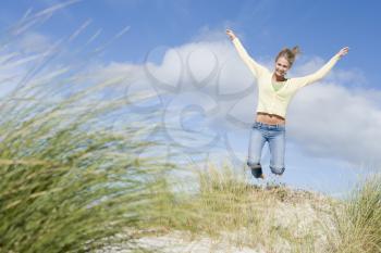 Royalty Free Photo of a Girl Jumping Over Sand Dunes