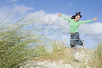 Royalty Free Photo of a Girl Jumping in the Sand