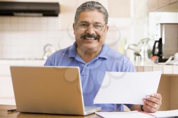 Royalty Free Photo of a Man in a Kitchen With a Laptop