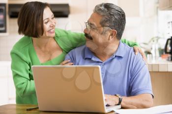 Royalty Free Photo of a Couple in the Kitchen With a Laptop
