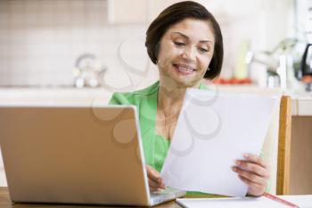 Royalty Free Photo of a Woman in the Kitchen With a Laptop