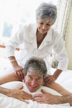 Royalty Free Photo of a Woman Giving a Man a Backrub in the Bedroom