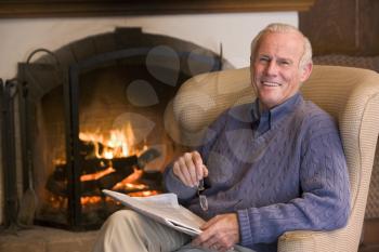 Royalty Free Photo of a Man With a Newspaper Beside a Fireplace