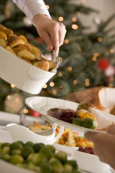 Royalty Free Photo of a Person Serving Roast Potatoes at Christmas Lunch