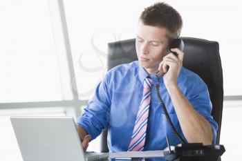 Royalty Free Photo of a Man With a Laptop on the Telephone