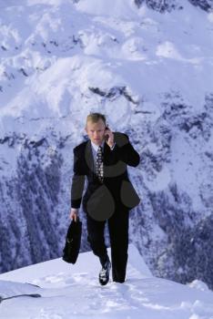 Royalty Free Photo of a Businessman Climbing a Mountain With a Cellphone
