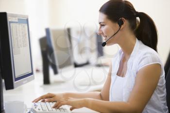 Royalty Free Photo of a Woman Wearing a Headset at a Computer
