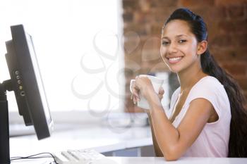 Royalty Free Photo of a Woman at a Computer Drinking Coffee