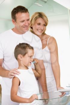 Royalty Free Photo of a Boy Brushing His Teeth With His Parents Watching  