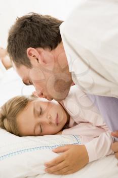Royalty Free Photo of a Man Kissing His Daughter in Bed