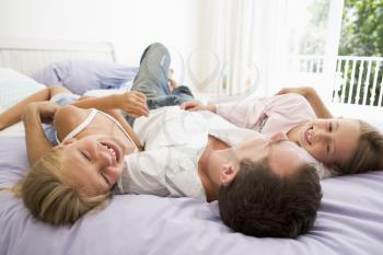 Royalty Free Photo of a Father With His Two Daughters on a Bed