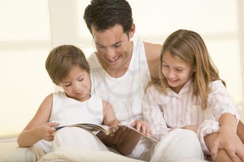 Royalty Free Photo of a Man and Two Children Reading in Bed
