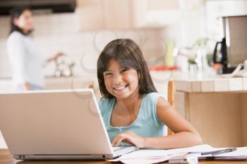 Royalty Free Photo of a Girl at a Laptop in the Kitchen