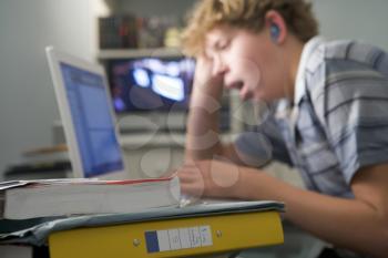 Royalty Free Photo of a Boy at a Laptop Listening to Music and Yawning
